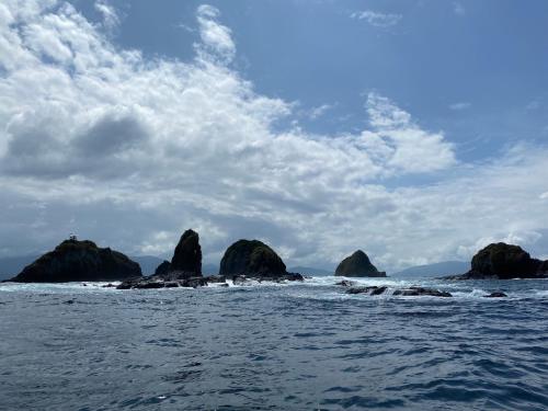 a group of rocks in the ocean under a cloudy sky at Choibana Ecolodge in Bahía Solano