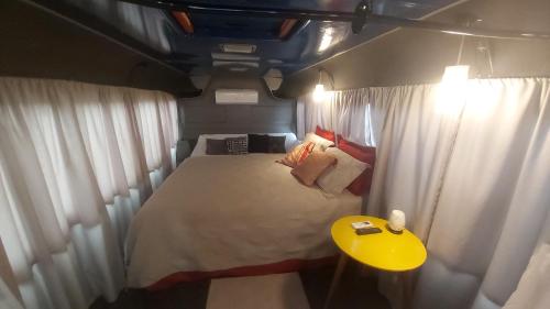 a small bedroom with a bed and a yellow table at LolosaBUS - Não é apenas uma hospedagem e sim uma EXPERIÊNCIA! in Ubatuba