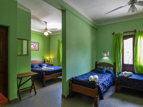 two beds in a room with green walls at Hostal Mirador del Valle in Cafayate