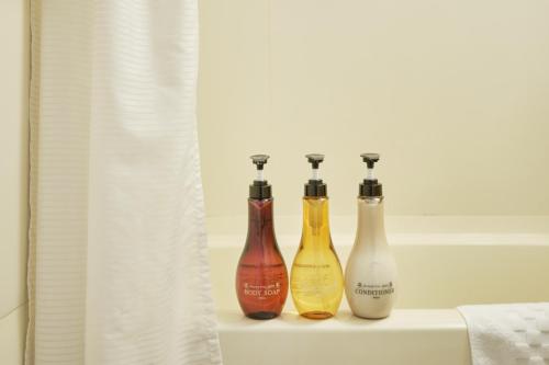 three bottles sitting on a window sill in a bathroom at Pod Select Hotel Shinjuku in Tokyo