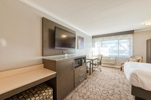 a hotel room with a bed and a desk with a television at Amanzi Hotel, an Ascend Collection Hotel in Ventura