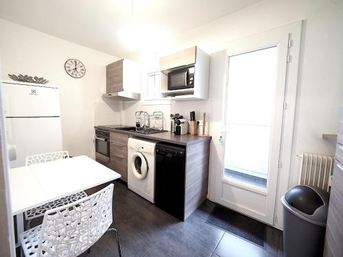 une cuisine avec lave-linge et sèche-linge à côté d'une fenêtre dans l'établissement LE CALLOU - Parking - Face aux Thermes - Rez de Chaussée, à Vichy