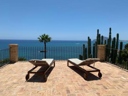 a patio with two chairs and a table and a fence at El jardin Botánico Villa LUZ in Altea