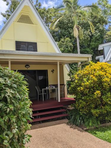 a yellow house with a porch with a table at Canopy 5 Chalet in Nelly Bay