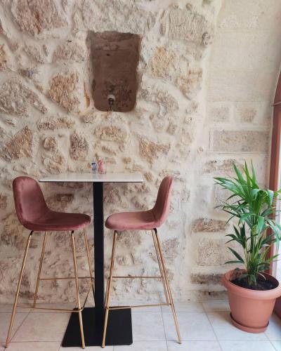 a table and two chairs in front of a stone wall at Archontiko Old Town Suites in Rethymno Town