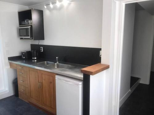 a kitchen with a sink and a microwave at Frangipani guesthouse -Ngunguru in Whangarei