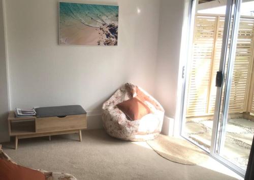 a living room with a chair and a window at Frangipani guesthouse -Ngunguru in Whangarei