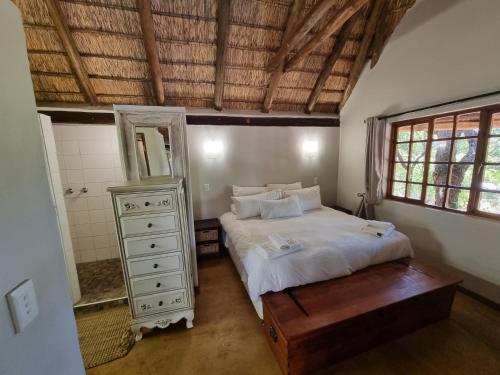 une chambre avec un lit avec une commode et un miroir dans l'établissement Milkwood Cottage Mabalingwe, à Bela-Bela