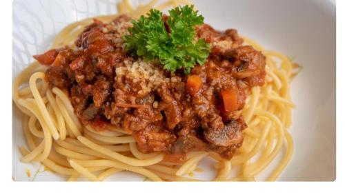 a plate of spaghetti with meat sauce and parsley on it at Kuntum Cottage Bed & Breakfast in Kampong Tanjong Ipoh