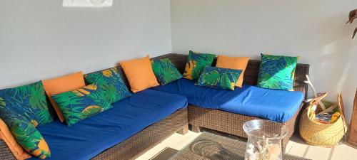 a blue couch with colorful pillows in a room at Esprit caraïbes in Le Diamant