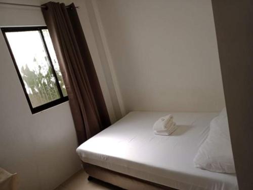 a small bedroom with a white bed with a window at Lei Kendee in Digos