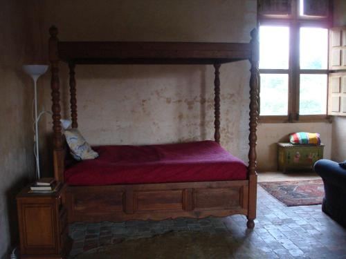 a canopy bed with a red mattress and a window at Manoir de la Baronnie in Marcei
