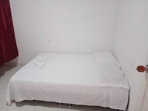 a white bed with a white blanket on it at Hospedaje El Cerrito 2 in El Cerrito