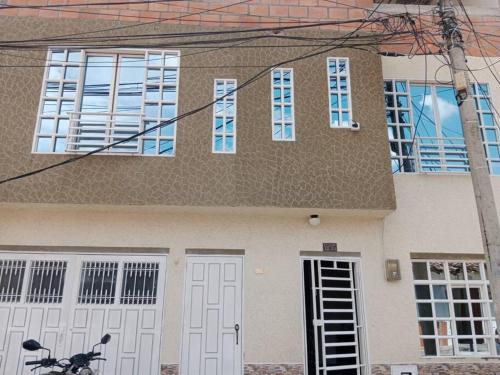 a house with white doors and a bike in front of it at Hospedaje El Cerrito 2 in El Cerrito