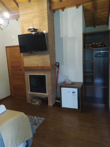 a living room with a tv and a fireplace at Pousada Alto dos Pinheiros in Monte Verde