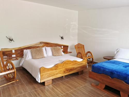 a bedroom with a wooden bed and two chairs at Hospedaje Vista Hermosa Salento in Salento