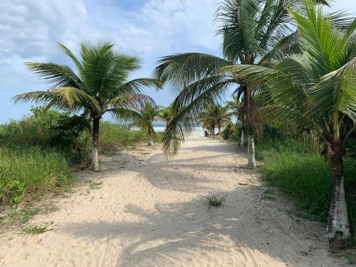 a dirt road with palm trees on a beach at Apto novo pertinho da praia em Boracéia, Bertioga in Bertioga