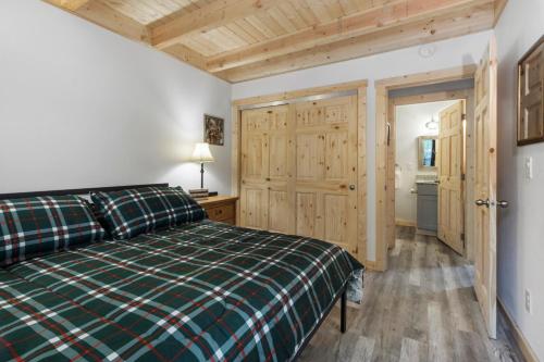 a bedroom with a green plaid bed and a bathroom at Kelton's Cabin in Ashford