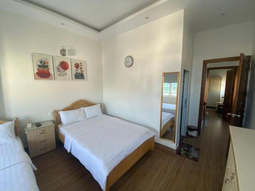 a bedroom with a white bed and a mirror at CSLTDL Minh Hùng in Da Lat