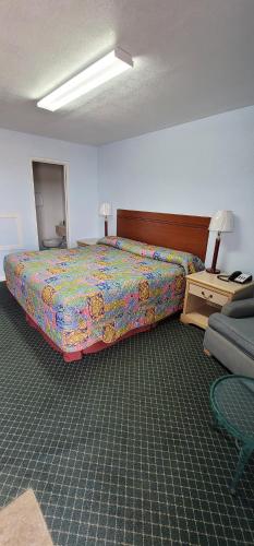 a bedroom with a bed with a colorful bedspread and a table at Longhorn Motel Boise City in Boise City