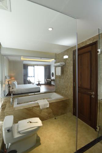a bathroom with a sink and a bed and a mirror at Phu Cuong Hotel Ca Mau in Cà Mau