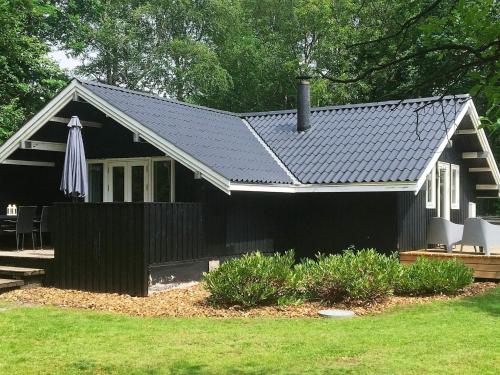 una casa negra con un paraguas en un patio en 6 person holiday home in Toftlund en Vestergård