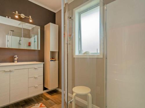 a bathroom with a shower and a sink and a stool at Hosts on the Coast View to Mercury in Whitianga