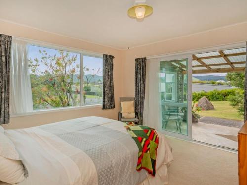 a bedroom with a bed and a large window at Hosts on the Coast Views to Mercury in Whitianga