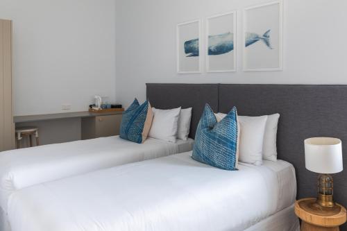 two beds in a room with blue and white pillows at The Clovelly Hotel in Sydney