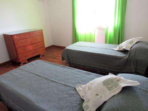 two beds in a room with green curtains and a dresser at Duplex Villanueva in San Rafael