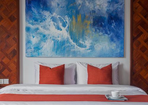 a bedroom with a bed with orange pillows and a painting at Homewood Hotel By Seuya Hotel in Siem Reap