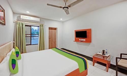 a bedroom with a bed and a tv on the wall at Treebo Sidhartha International Baliapanda in Puri
