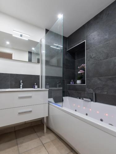 une salle de bain avec une baignoire et un lavabo et un tubermott dans l'établissement CABANA & Le Saint Amour - Centre-Ville, à Villefranche-sur-Saône