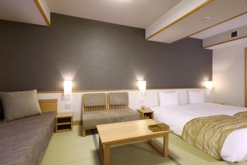 a hotel room with two beds and a couch at Oyado Tsukiyo no Usagi in Izumo