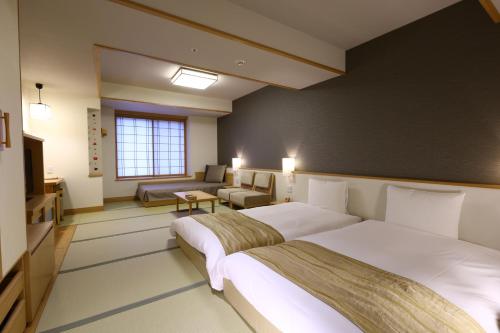 a hotel room with two beds and a couch at Oyado Tsukiyo no Usagi in Izumo