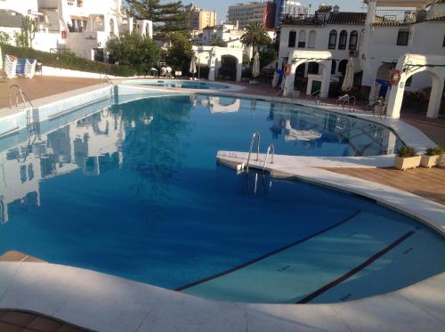 a large swimming pool with blue water at Pueblo Evita. Stunning sea and mountain views, close to amneties. in Benalmádena