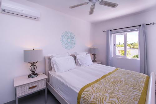 a white bedroom with a bed and a window at Le Mandala Moris in Pointe aux Cannoniers