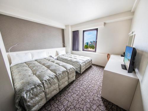a hotel room with two beds and a flat screen tv at Reisenkaku Hotel Kawabata in Fukuoka