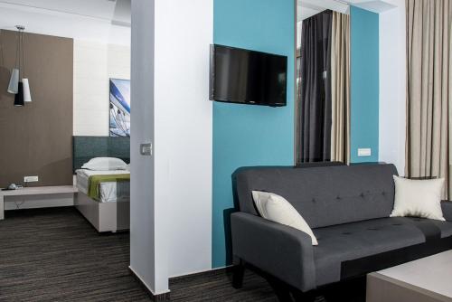a room with a couch and a tv on a wall at Hotel On Plonge Junior in Mamaia