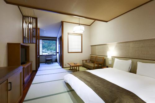 a hotel room with a bed and a television at Inishie no Yado Keiun in Izumo