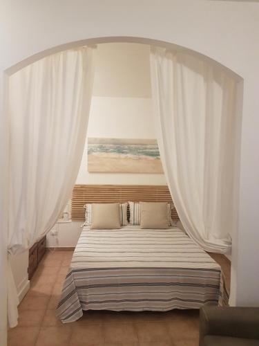 a bedroom with a large bed with white curtains at Appartamentino tipico nel centro in Corniglia