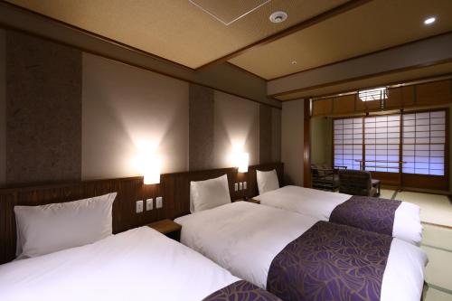 a hotel room with two beds with white sheets at Inishie no Yado Keiun in Izumo