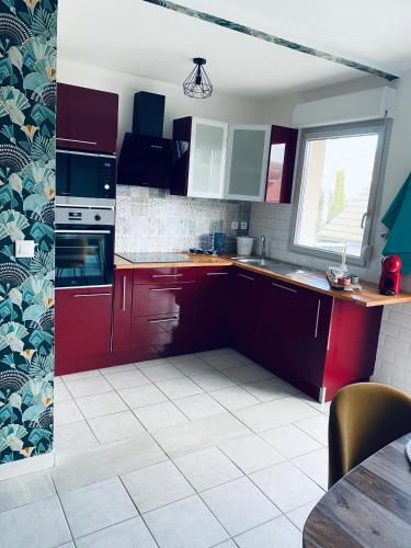 a kitchen with red cabinets and a white tile floor at Enjoy your dream in Mers-les-Bains