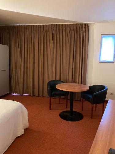 una camera d'albergo con tavolo, sedie e letto di De Rantere a Oudenaarde
