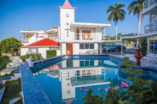 a swimming pool in front of a building with a clock tower at Hotel Laguna Bacalar in Bacalar
