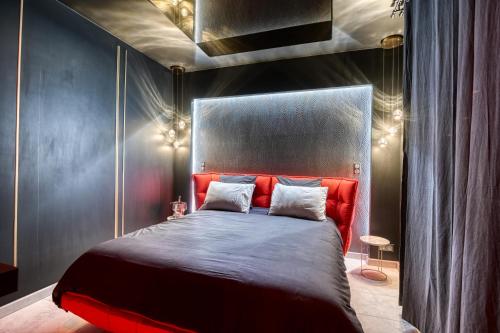 a bedroom with a bed with a red head board at Villa avec jacuzzi privatif in Saint-Cyr-lʼÉcole