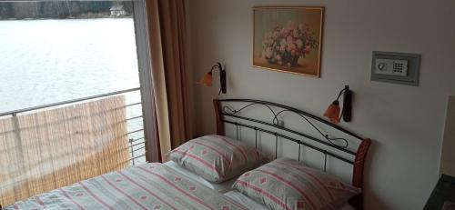 a bedroom with a bed with a window and a picture at Penzion Ratmírák in Malý Ratmírov