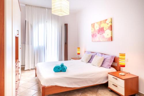 a bedroom with a white bed with a blue flower on it at Orange Villasimius House in Villasimius