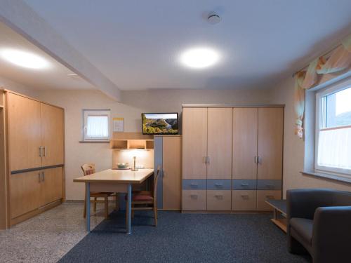 a room with a desk and cabinets and a table at JUNIPRO Apartments Haustadt in Beckingen