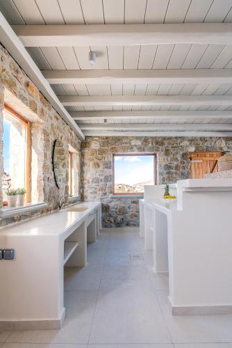 a bathroom with white sinks and a stone wall at Ethereal Villa Mykonos in Kalafatis